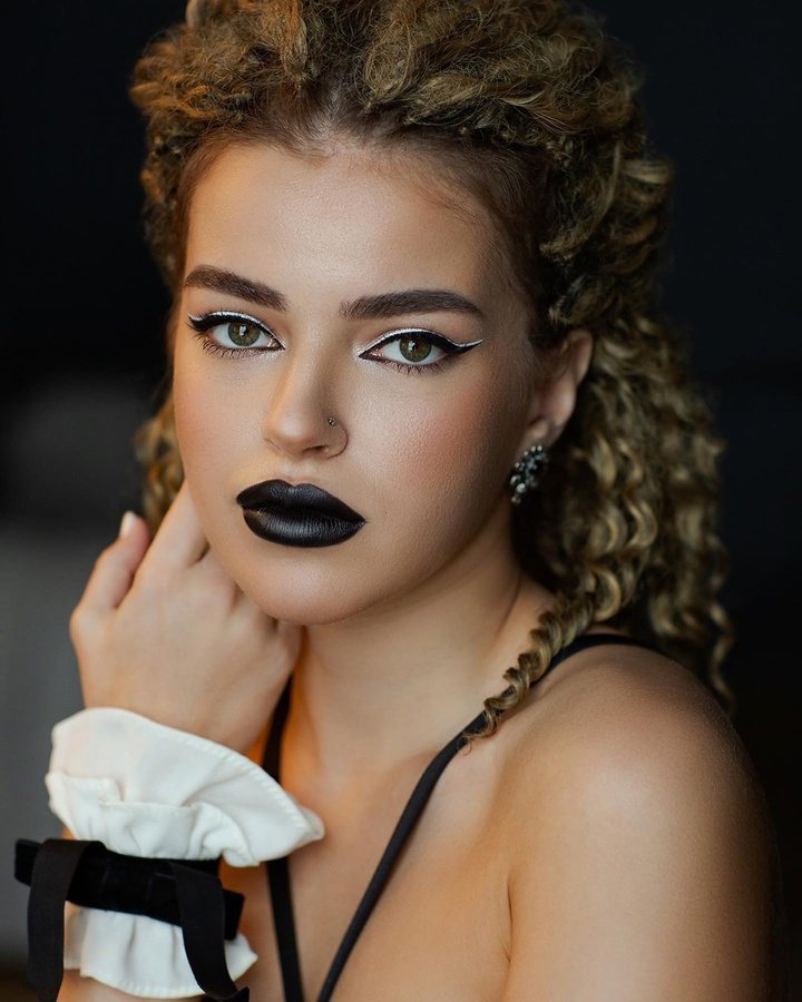 Creative look: black matte lips and graphic white liner on braided curls